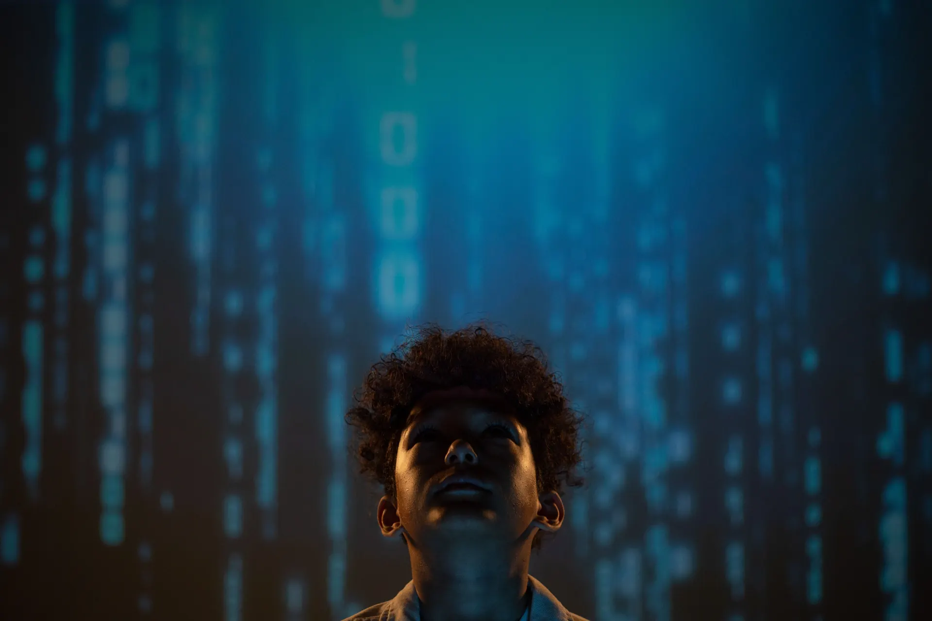 A young boy looking upward against a blue digital background, symbolizing a new generation in the age of AI