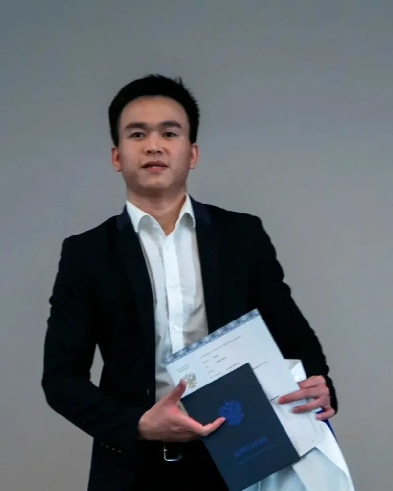 Tim Nguyen in a suit holding his diploma from Bauman Moscow State Technical University, 2022