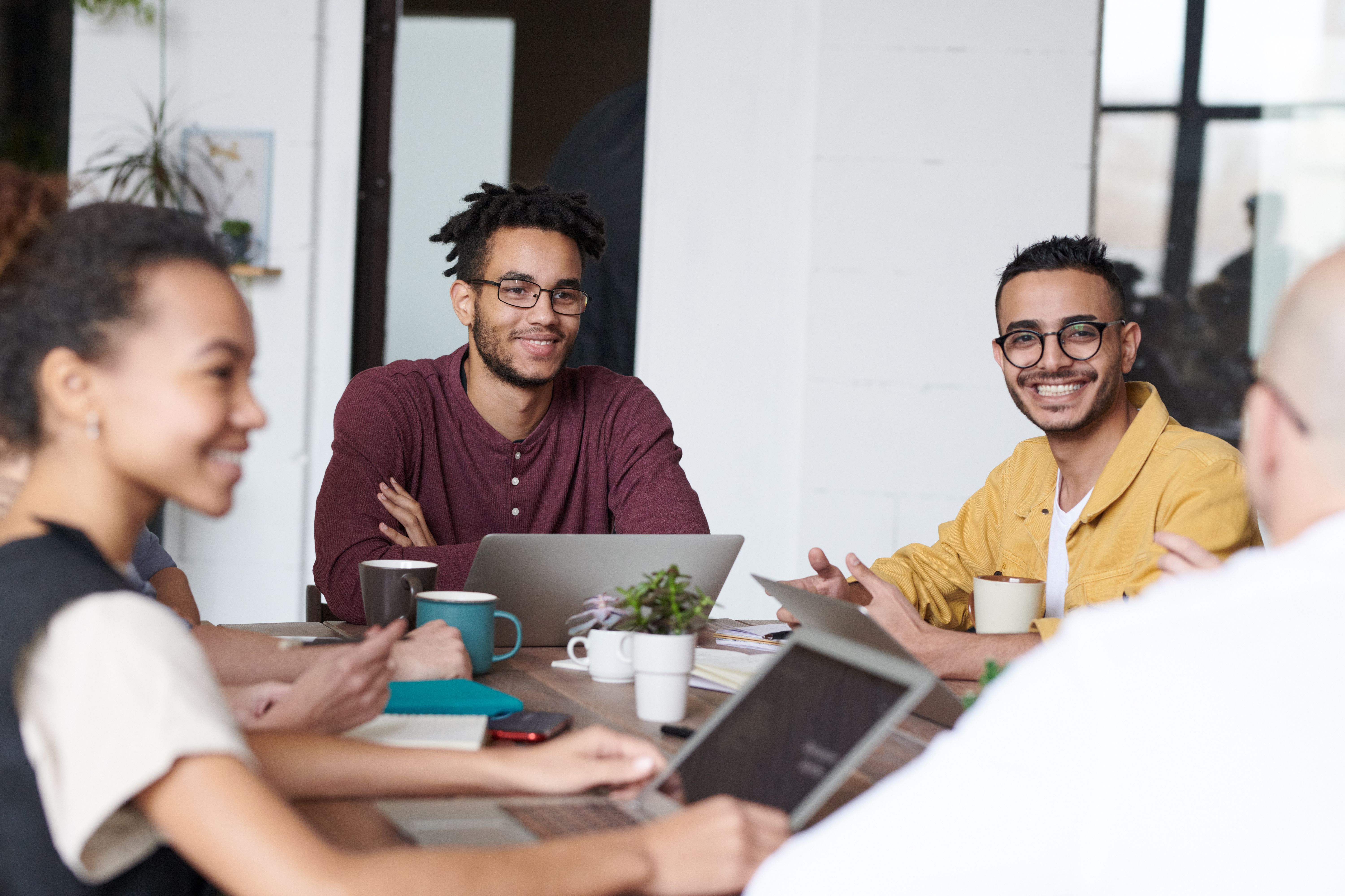 A diverse group of young professionals smiling and discussing ideas around a table
